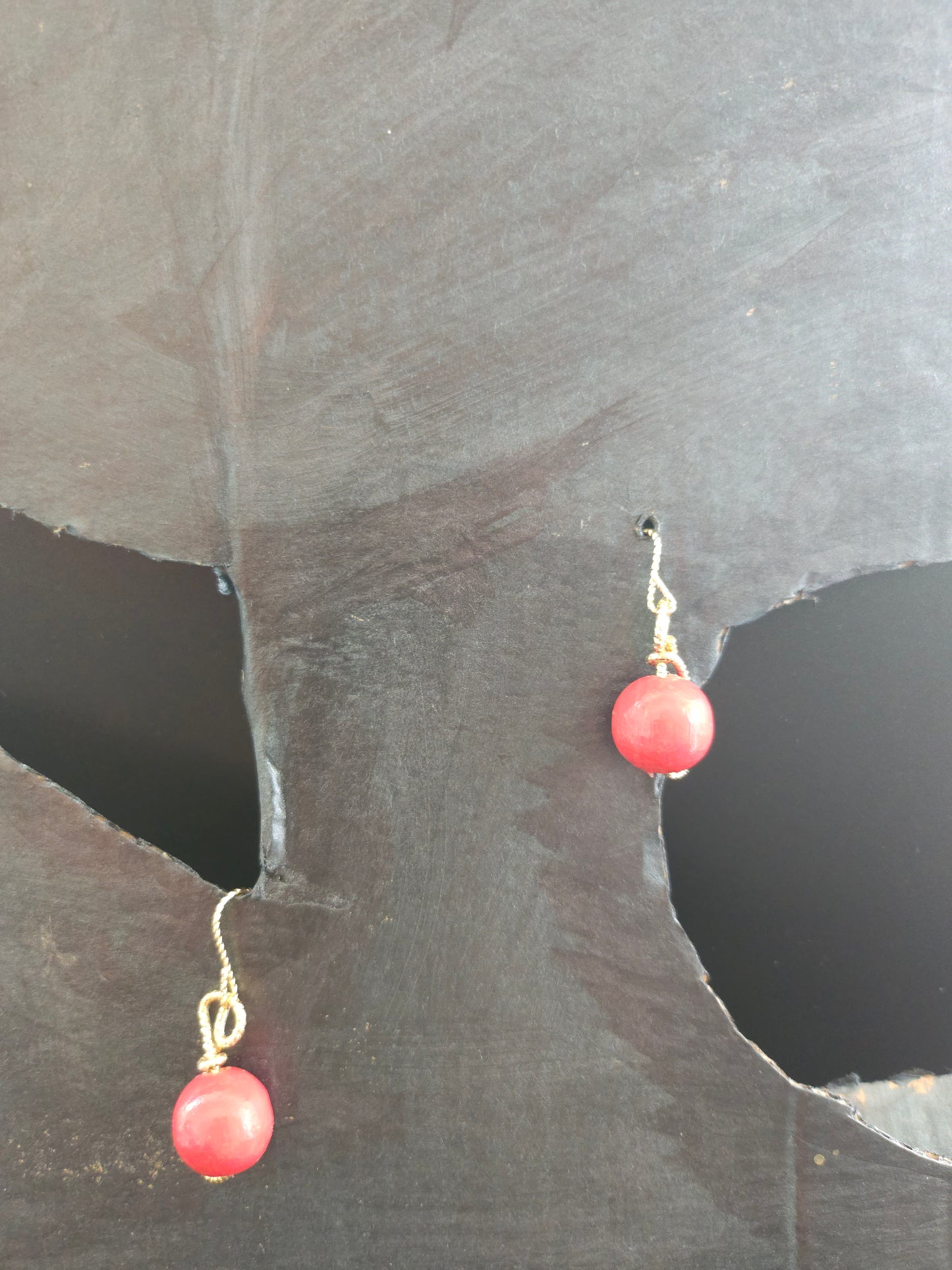 Vue rapprochée des perles en bois rouge entourées de fil plaqué or 18 carats