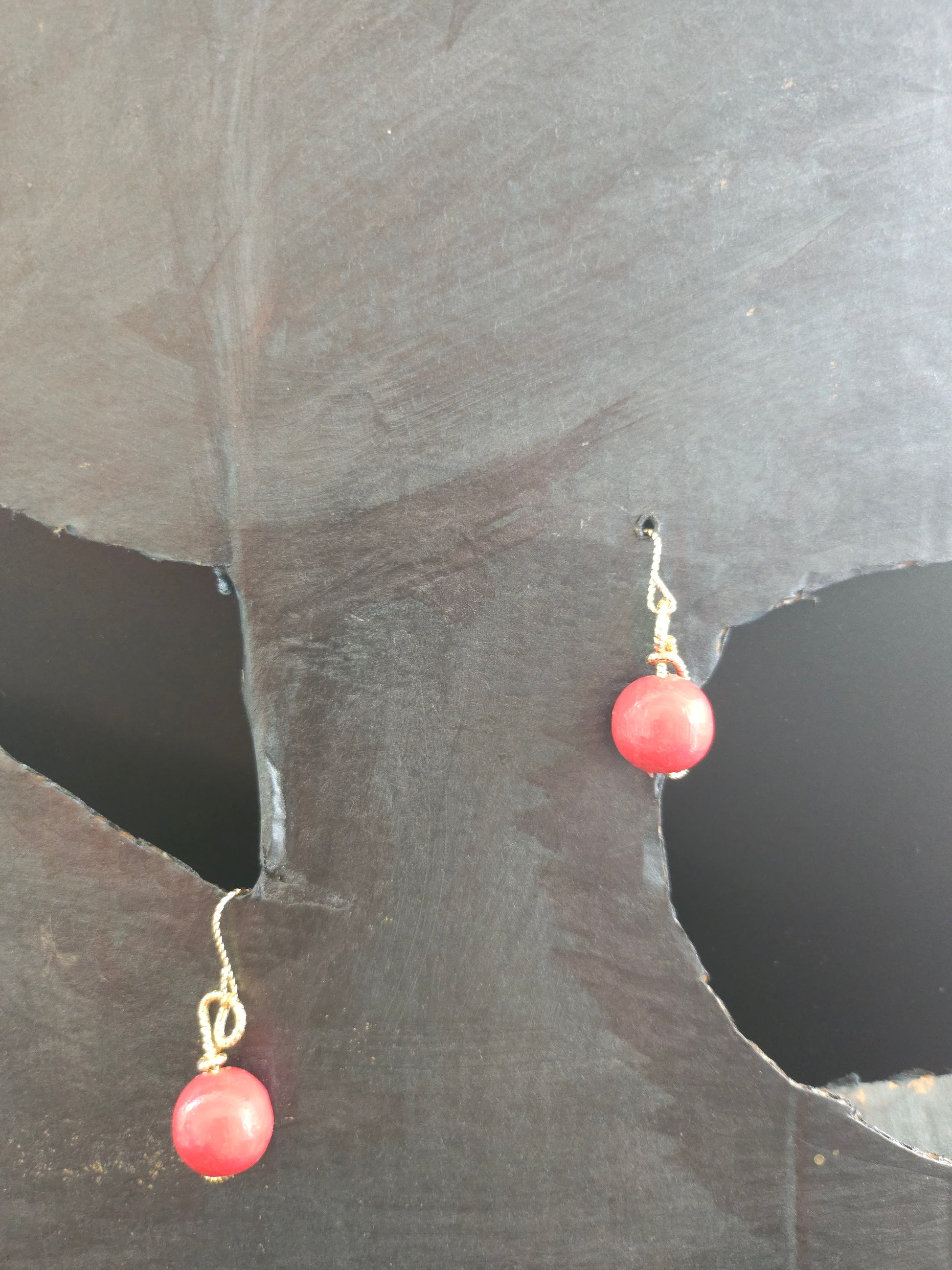 Vue rapprochée des perles en bois rouge entourées de fil plaqué or 18 carats