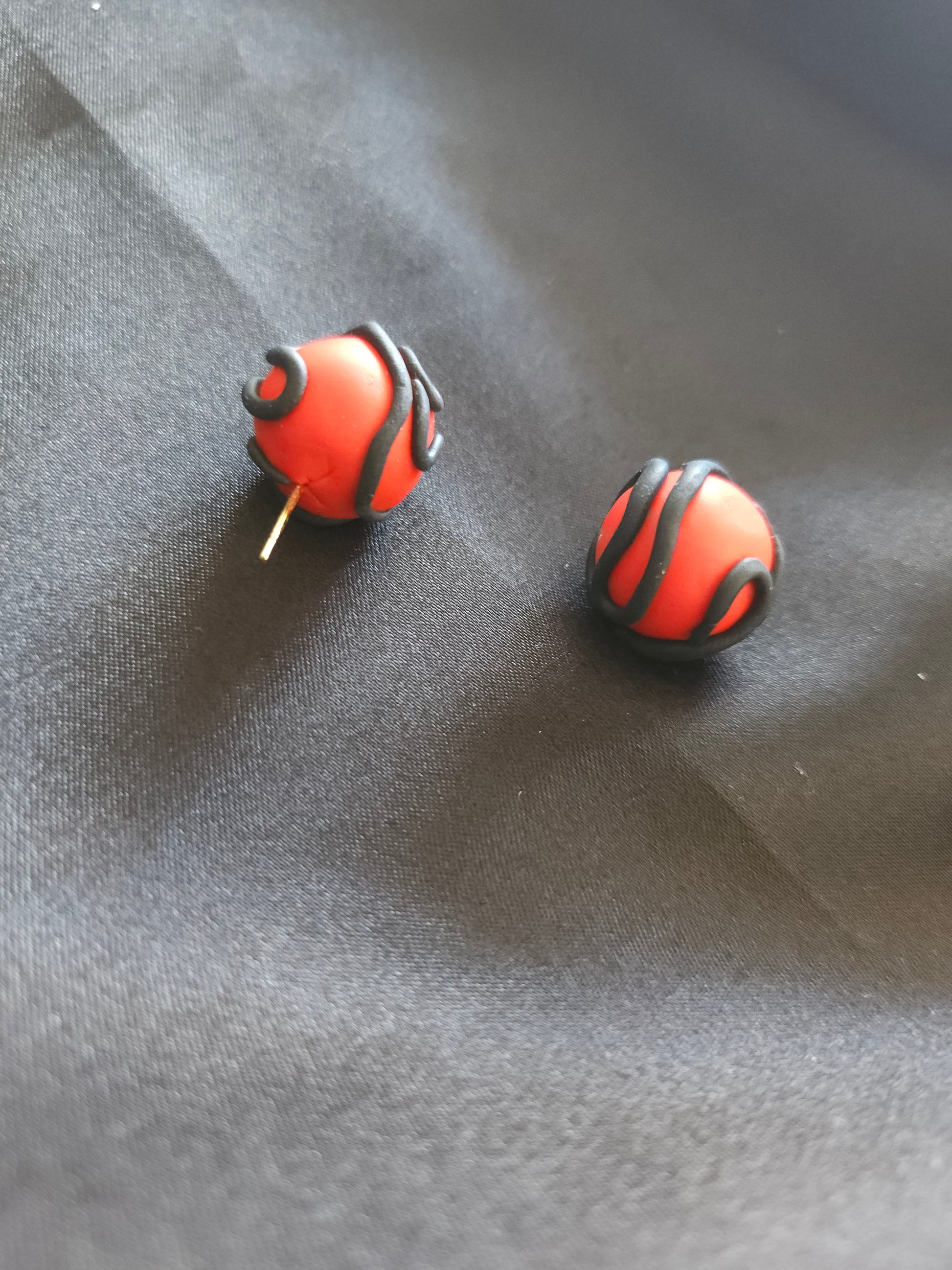 Puces d'oreilles rouges serpentées noires - vue d'ensemble du design artisanal