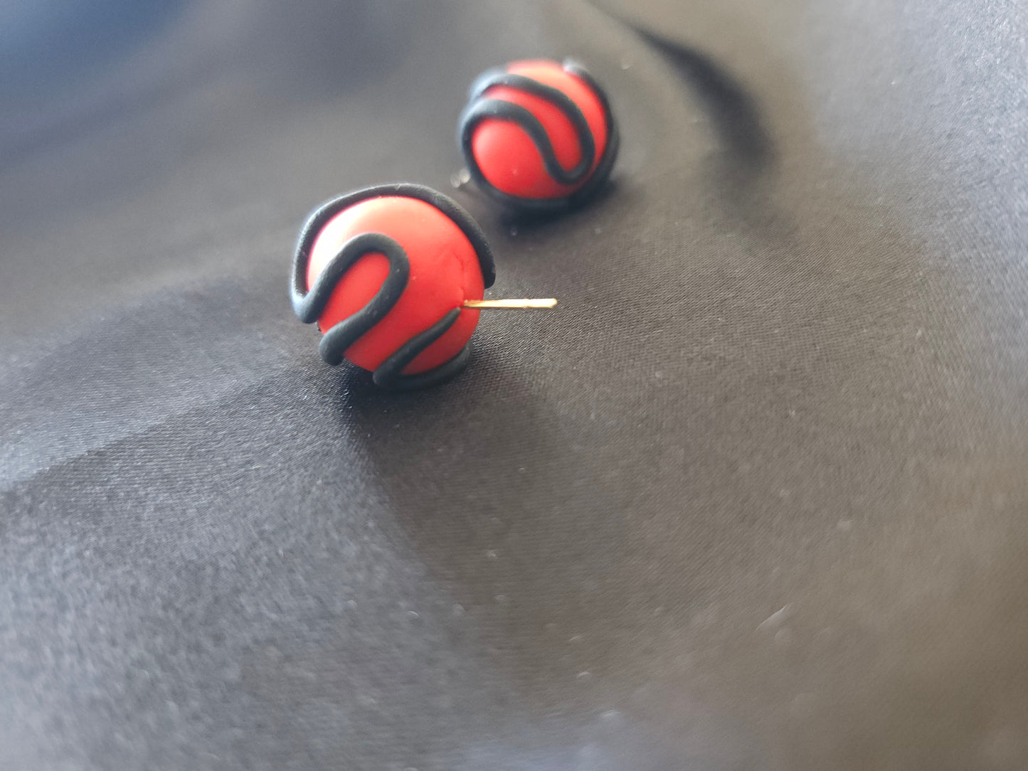 Puces d'oreilles rouges serpentées noires - vue d'ensemble du design artisanal