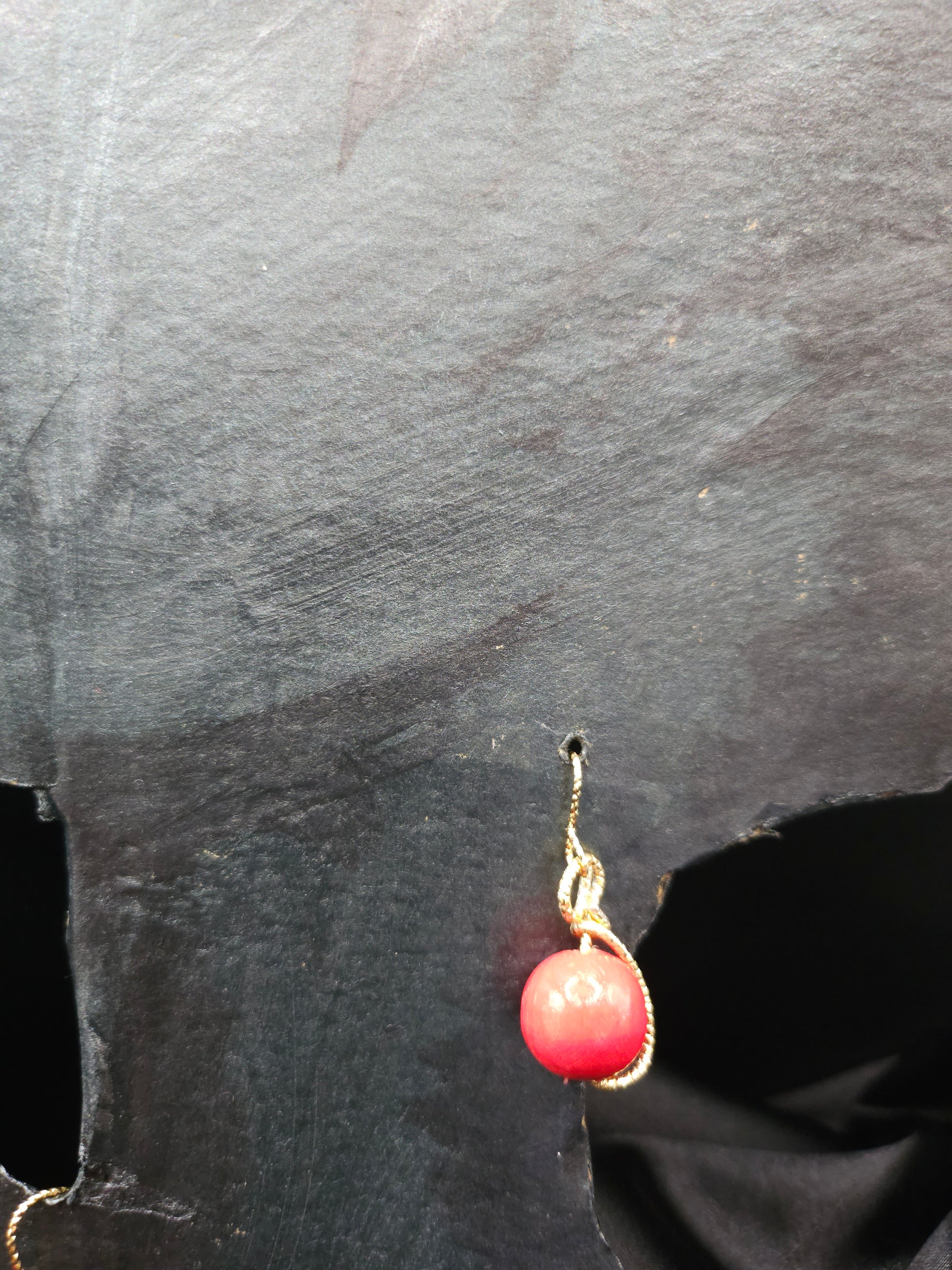 Détail des boucles d'oreilles rondes en bois rouge avec fil doré